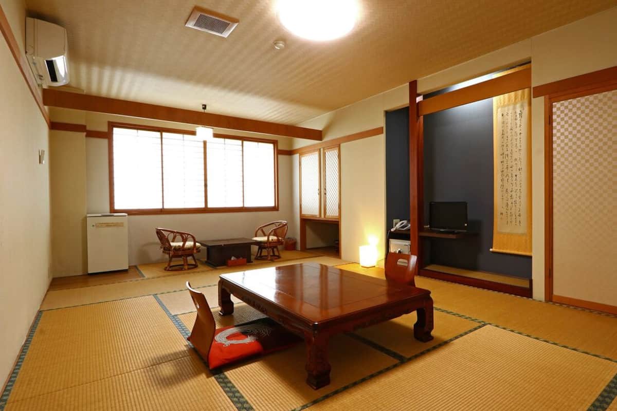 A traditional Japanese room with tatami flooring, a low table, a television, and sliding doors.