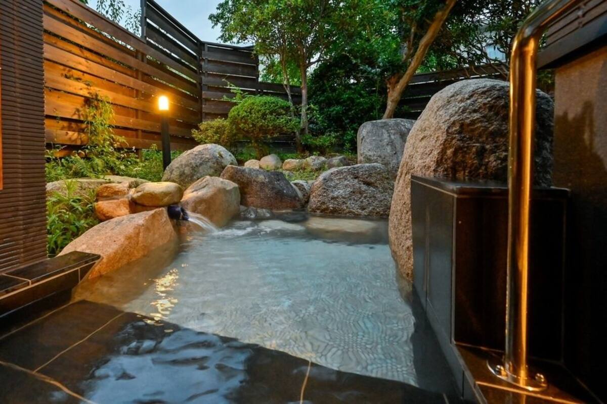A spa area with a hot spring, large rocks, and a wooden fence.
