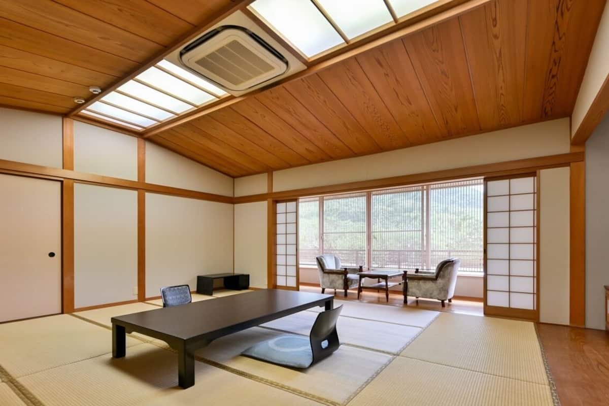 A traditional Japanese-style room with tatami flooring, a low table, chairs, and sliding doors.