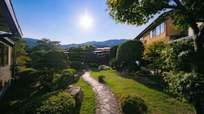 A courtyard with a stone pathway, neatly trimmed hedges, and a view of distant hills. - Yuno Onsen Hozanen (Shunan)