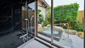 Un baño moderno con cabina de ducha de vidrio, un jacuzzi y vistas a un jardín ajardinado.