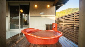 Una terraza de madera con un jacuzzi y una valla de madera.