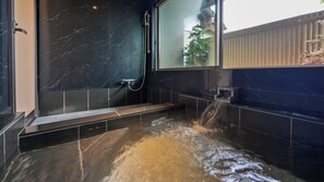 Un baño moderno con pared de mármol, ducha y bañera con agua corriente.