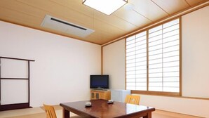 A conference room with a wooden table, chairs, a television, and tatami mats.