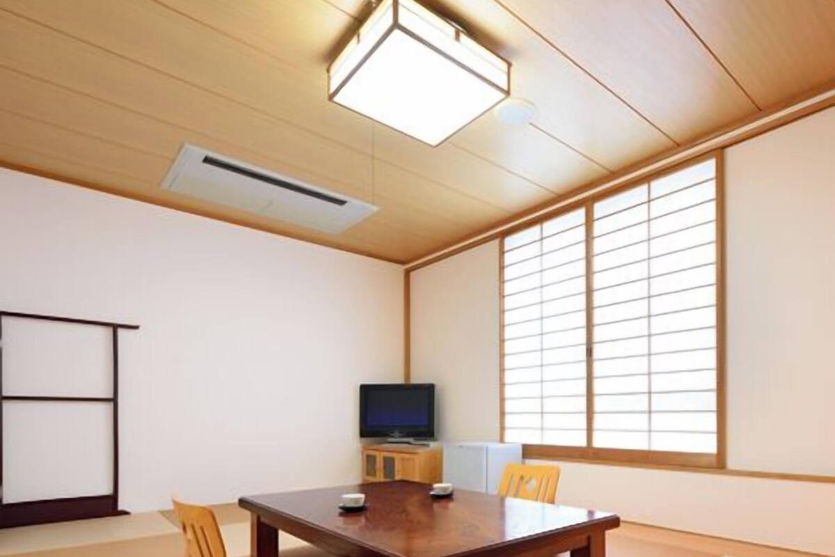 Une salle de conférence avec une table en bois, des chaises, un téléviseur et des tatamis.