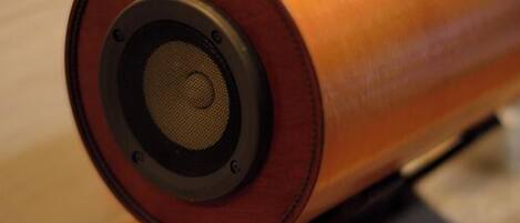 A cylindrical object with a speaker grille, possibly a decorative item, on a stand.