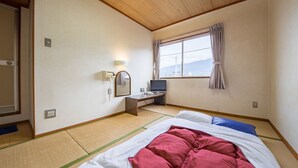 Una camera d'albergo con un letto, una scrivania con un computer, uno specchio e una finestra con tende.