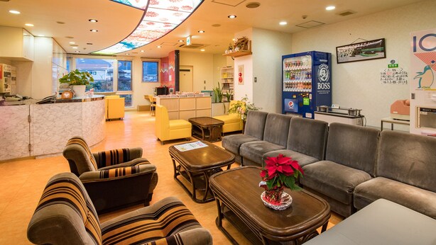 Una hall d'hotel con posti a sedere, una reception, un distributore automatico e una grande finestra.