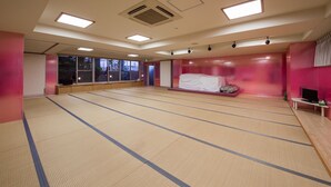 Un'ampia stanza con tatami, un letto, una televisione e grandi finestre.