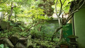 Un exuberante jardín con rocas, helechos y un farol de piedra.