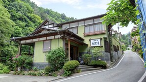 Un edificio japonés tradicional con techo inclinado, vigas de madera y un letrero que indica que es un templo.