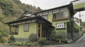 A traditional Japanese building with a green exterior, a tiled roof, and a sign with Japanese characters. - Shimobe Onsen Motoyu Ryokan Daikokuya (Minobu)