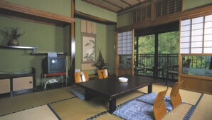 Una habitación japonesa tradicional con suelo de tatami, una mesa baja y un televisor sobre un soporte.