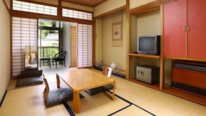 A traditional Japanese room with tatami flooring, a low table, a television, and a cabinet.