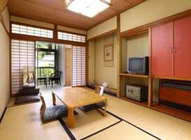 Una habitación japonesa tradicional con suelo de tatami, una mesa baja, un televisor y un armario.