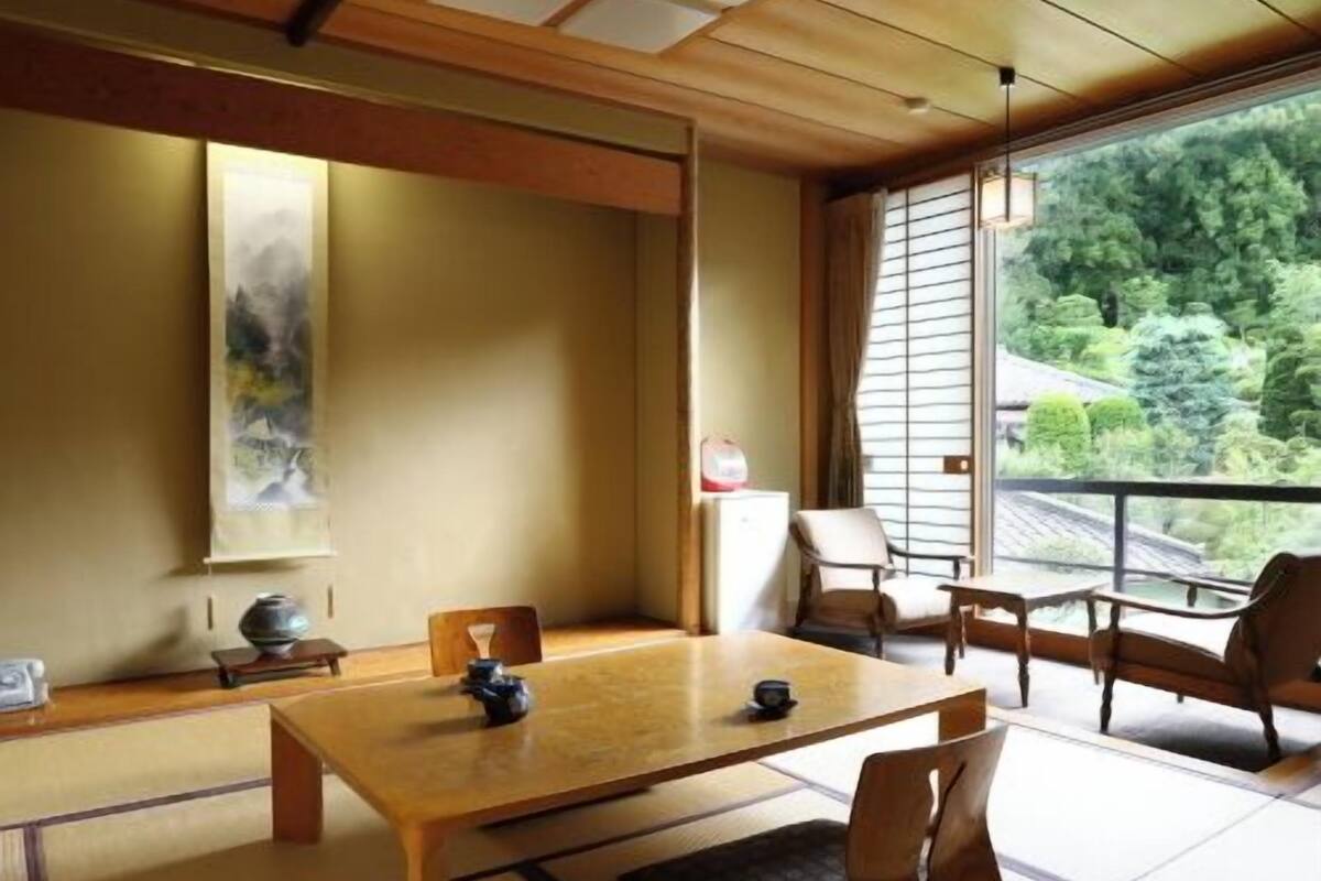 Una habitación japonesa tradicional con suelo de tatami, una mesa de madera baja y puertas correderas shoji.