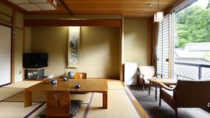 A traditional Japanese room with tatami flooring, a low table, a television, and a sliding door.