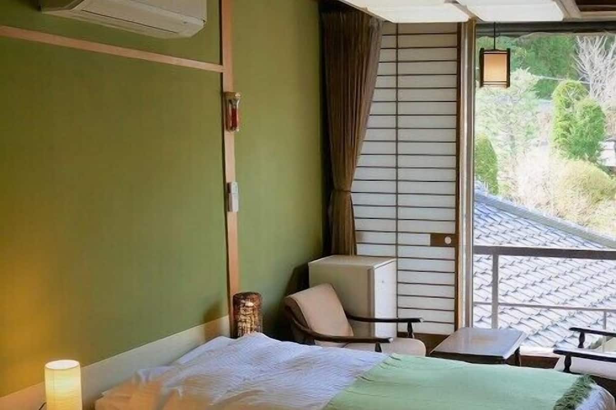 Habitación de hotel con dos camas, una silla, una mesa y vistas al exterior.