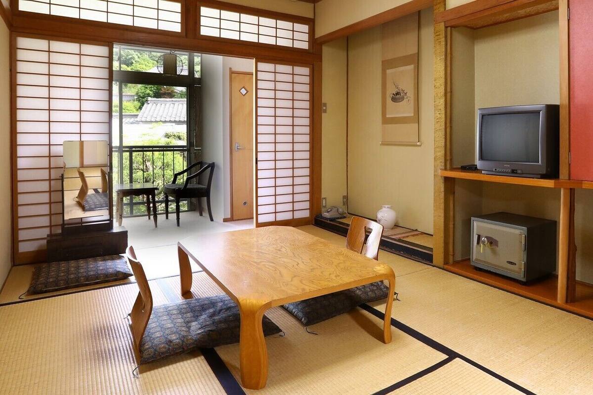 Una habitación japonesa tradicional con suelo de tatami, una mesa baja, un televisor y un armario.