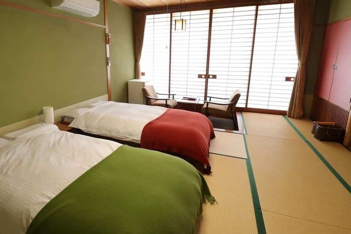 Una habitación con dos camas, una silla, una mesa y un ventanal con vistas.