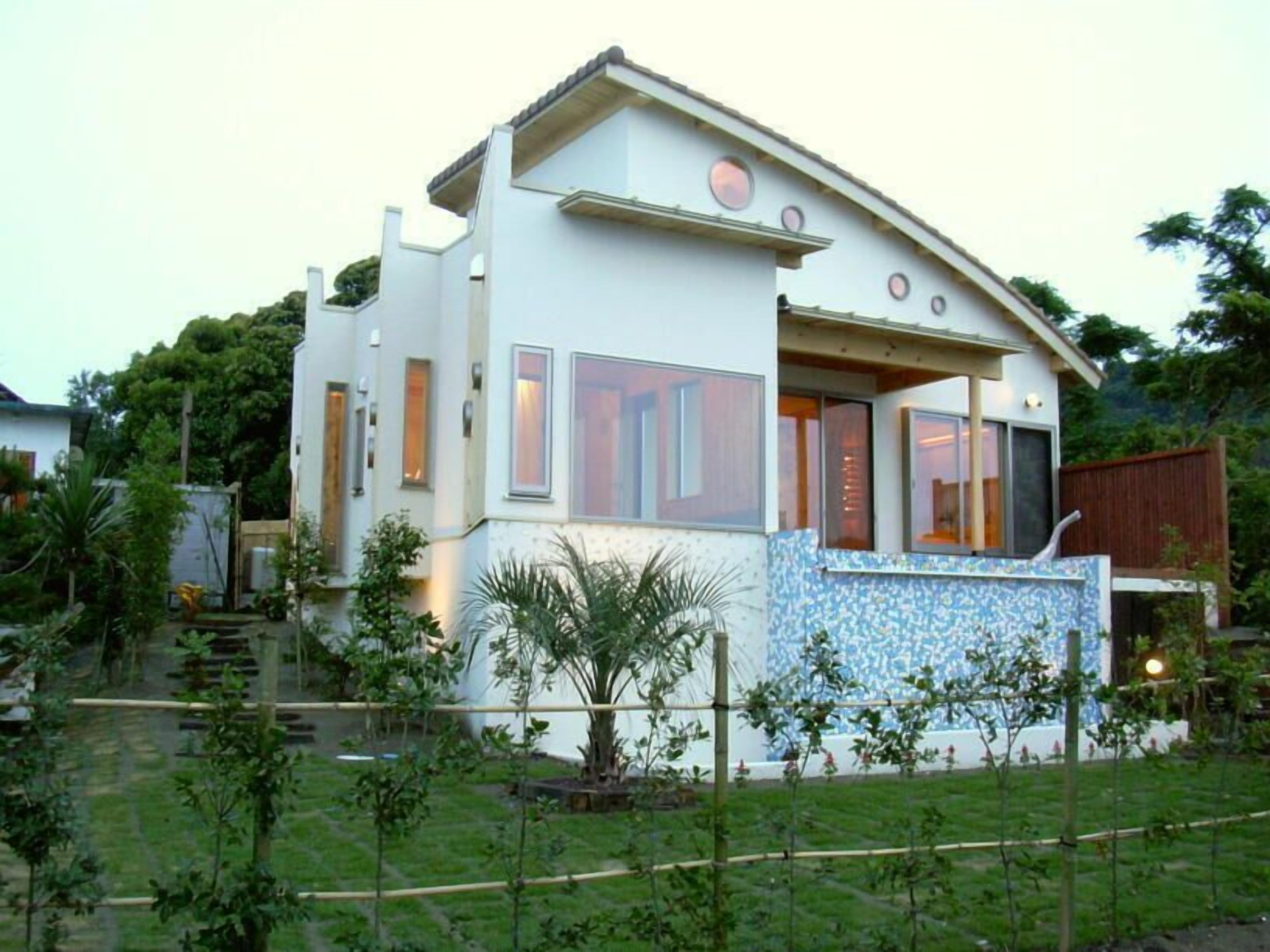 A modern two-story house with a curved roofline, large windows, and a tiled exterior wall.