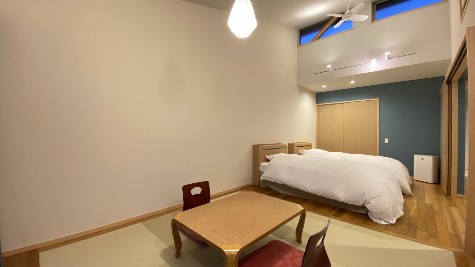 A bedroom with a bed, a table, and a chair.