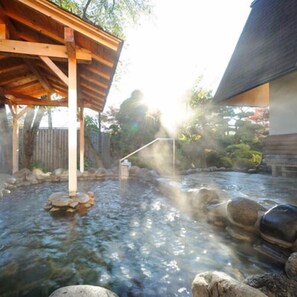 A hot spring area with a wooden structure, rocks, and a clear view of the surrounding landscape. - Gonohe Makiba Onsen (Gonohe)
