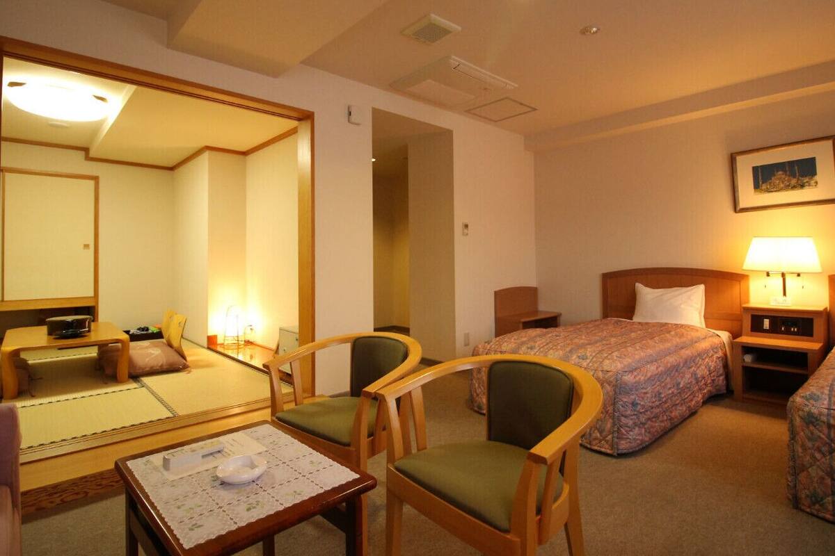 Une chambre d’hôtel comprenant un lit, un bureau, une chaise, une petite table et un miroir.