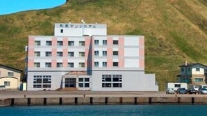 Un edificio de varios pisos con techo plano, una entrada central y un estacionamiento al frente.