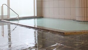 Una piscina con pared de azulejos y escalera metálica.