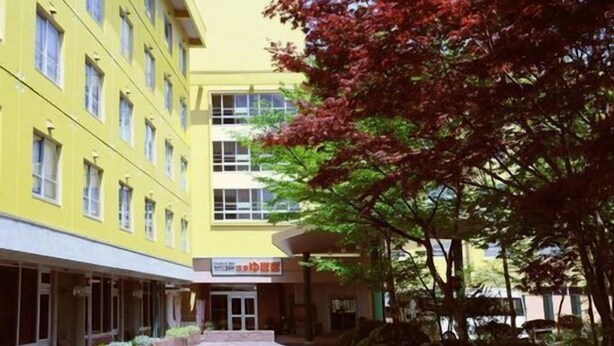 A yellow building with multiple windows and a covered entrance.