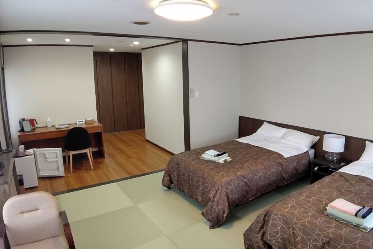 Una habitación de hotel con dos camas, un escritorio, una silla y un televisor.