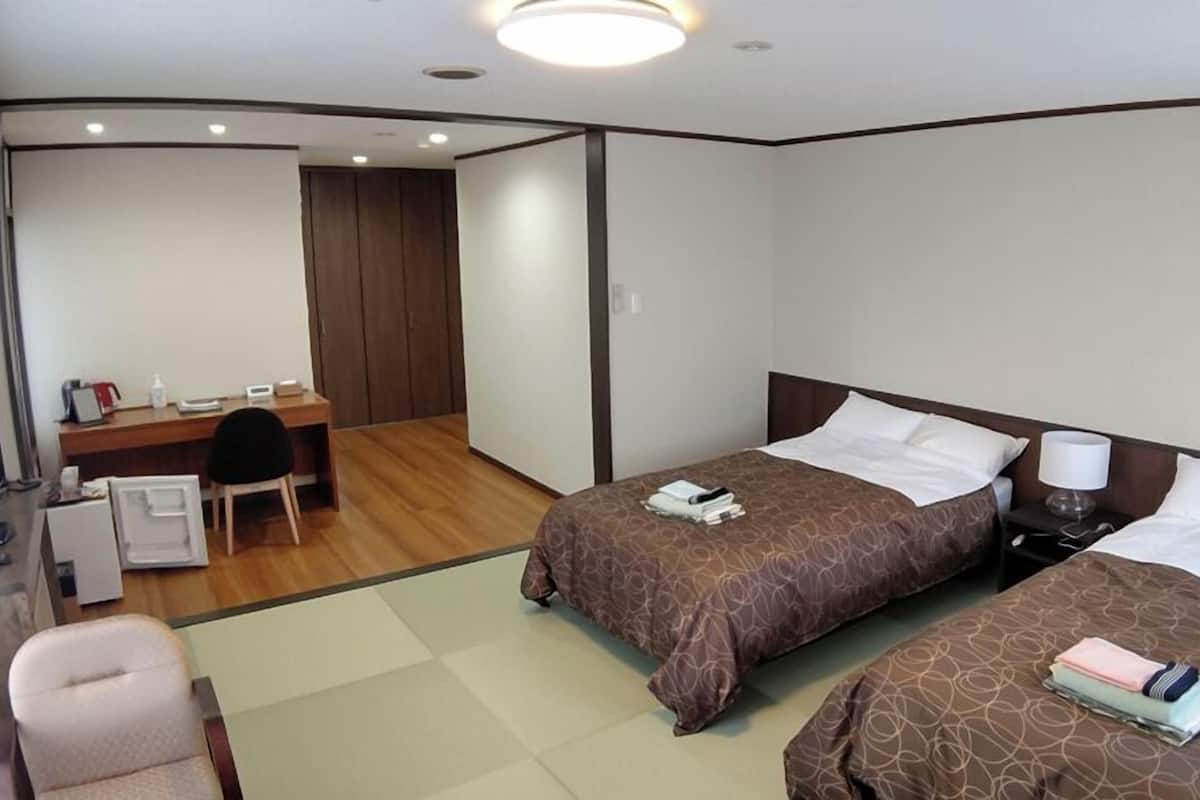 Ein Hotelzimmer mit zwei Betten, einem Schreibtisch, einem Stuhl und einem Fernseher.