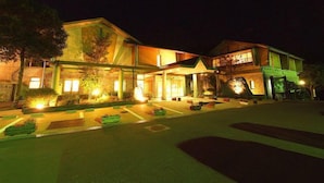 A two-story building with a well-lit entrance and a parking area. - Kamiyama Onsen Hotel Shikinosato & Iyashinoyu (Kamiyama)