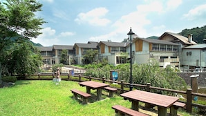 A hotel with multiple buildings, outdoor picnic tables, and a fenced garden area. - Kamiyama Onsen Hotel Shikinosato & Iyashinoyu (Kamiyama)