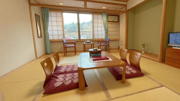 A traditional Japanese-style room with tatami flooring, a low table, and wooden chairs. - Kamiyama Onsen Hotel Shikinosato & Iyashinoyu (Kamiyama)