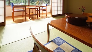 A traditional Japanese room with tatami flooring, a low wooden table, and a view of a mountainous landscape through large windows. - Kamiyama Onsen Hotel Shikinosato & Iyashinoyu (Kamiyama)