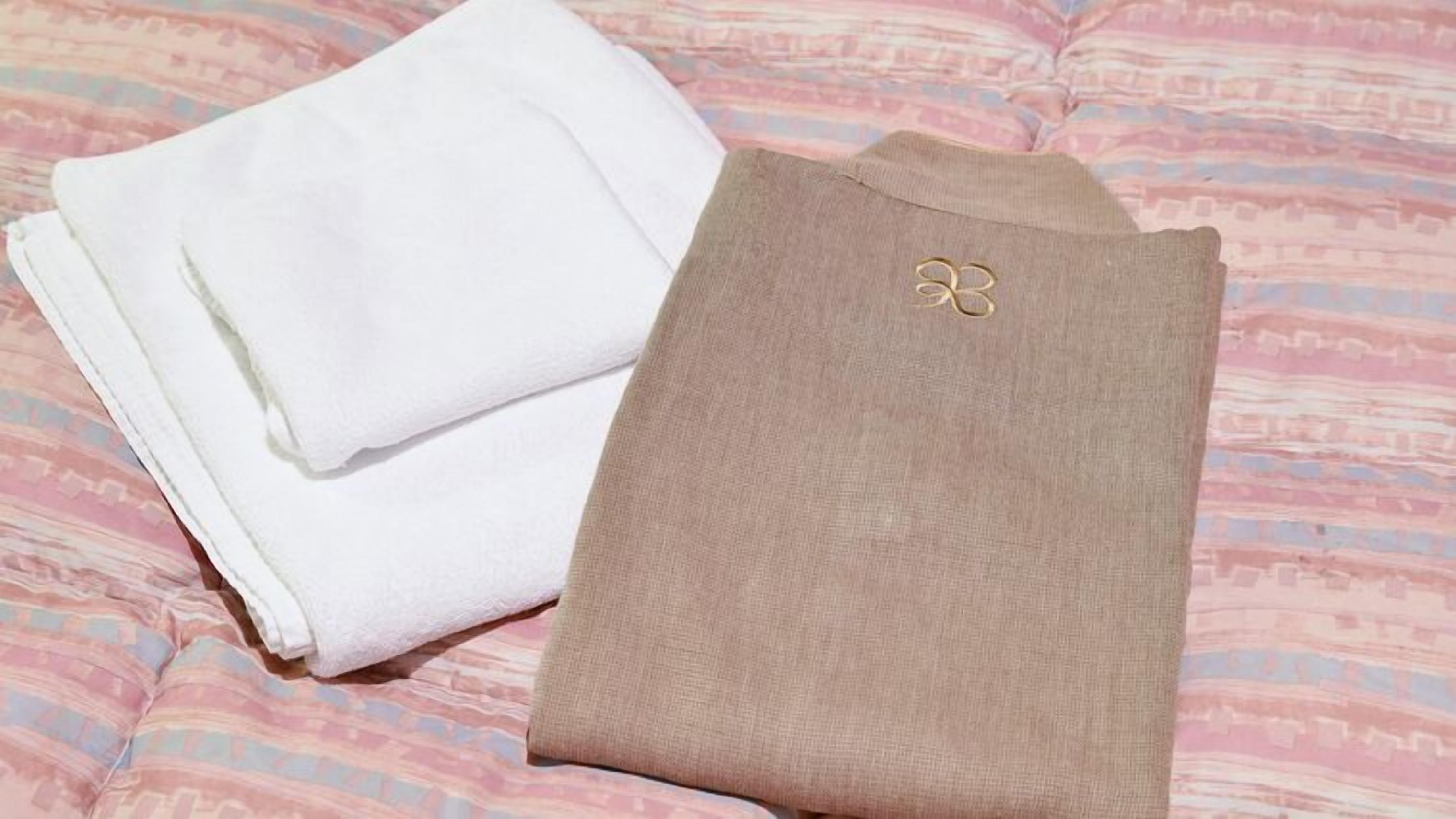 Un lit avec une couvre-lit à motifs et des serviettes blanches et beiges pliées.