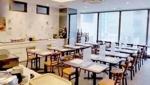 A dining area with tables and chairs, a kitchen counter, and large windows. - Hotel Sun Royal Kawasaki (Kawasaki)