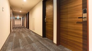 A hotel hallway with carpeted floors, wooden doors, and a ceiling light. - Hotel Sun Royal Kawasaki (Kawasaki)