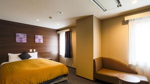 A hotel room with a bed, a chair, a small table, and artwork on the wall. - Hotel Sun Royal Kawasaki (Kawasaki)