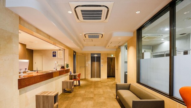A hotel lobby with a reception desk, seating area, and an elevator. - Hotel Sun Royal Kawasaki (Kawasaki)