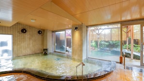 Relax in a serene onsen bath with a clear glass enclosure and wooden paneling.