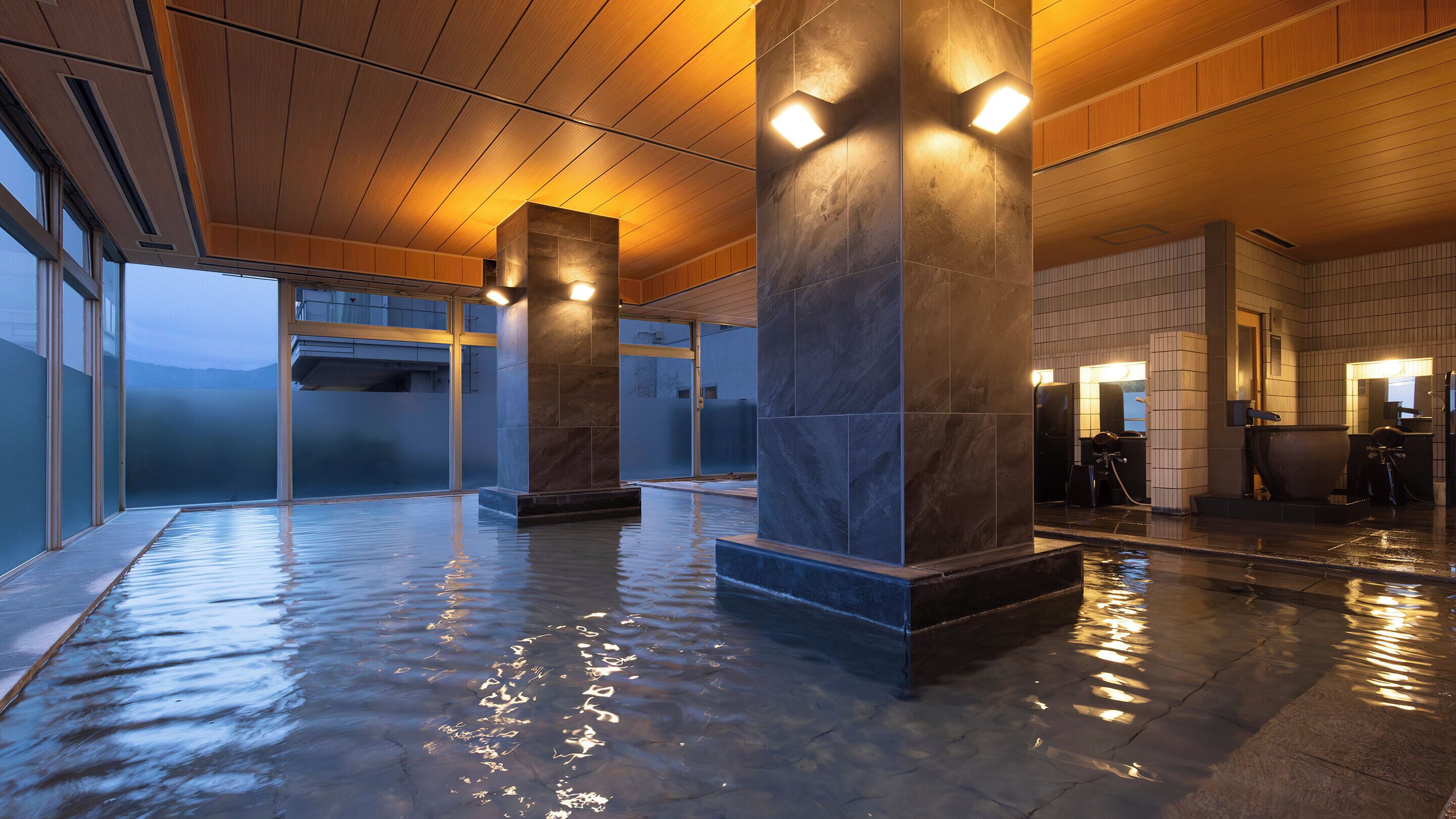A spacious indoor area with a wet floor, large pillars, and a modern design.