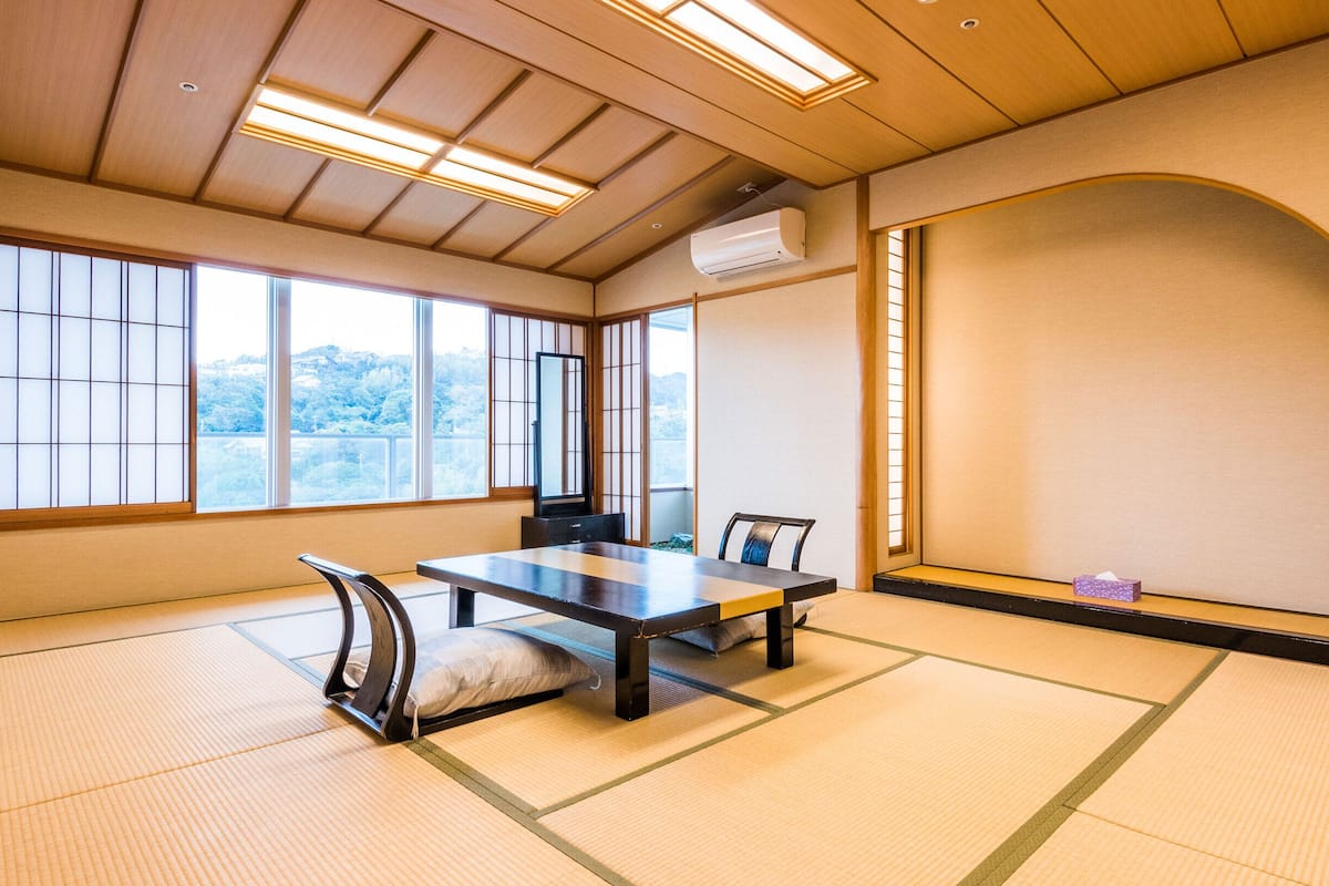 Um quarto japonês tradicional com tatames, uma mesa baixa e cadeiras.