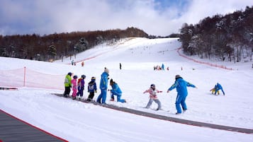 Pista de esqui coberta de neve, com esquiadores e snowboarders.