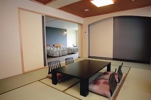 A traditional tatami mat room with a low table and chairs, a sliding door leading to a bedroom, and a large sliding screen.