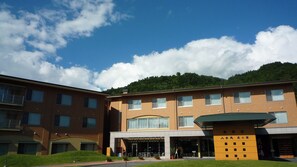 A multi-story building with a central courtyard, a covered outdoor seating area, and a sign indicating a restaurant. - Happoen Shika no Yu (Fujimi)