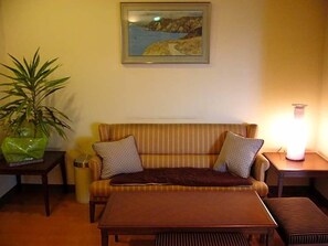 Una sala de estar con un sofá, una mesa, una lámpara y un cuadro en la pared.