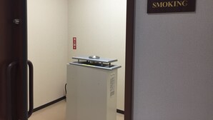 A hallway with a smoking sign on the wall, a fire alarm, and a trash bin. - Ageo Tobu Hotel (Ageo)